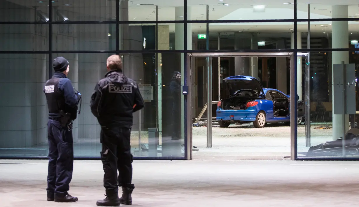 Polisi memeriksa kerusakan di lobi kantor Partai Sosial Demokratik Jerman (SPD) setelah sebuah mobil menabrakan gedung dengan sengaja di Berlin (25/12). Pelaku pria berusia 58 tahun menabrakan diri pada malam Natal. (AFP PHOTO / Ganjil Andersen)