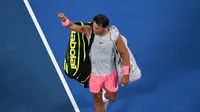 Petenis Spanyol, Rafael Nadal meninggalkan lapangan seusai memutuskan mundur saat melawan petenis Kroasia, Marin Cilic di perempat final Australia Terbuka 2018, Selasa (23/1). Nadal harus tersingkir karena mengalami cedera paha atas. (SAEED KHAN/AFP)