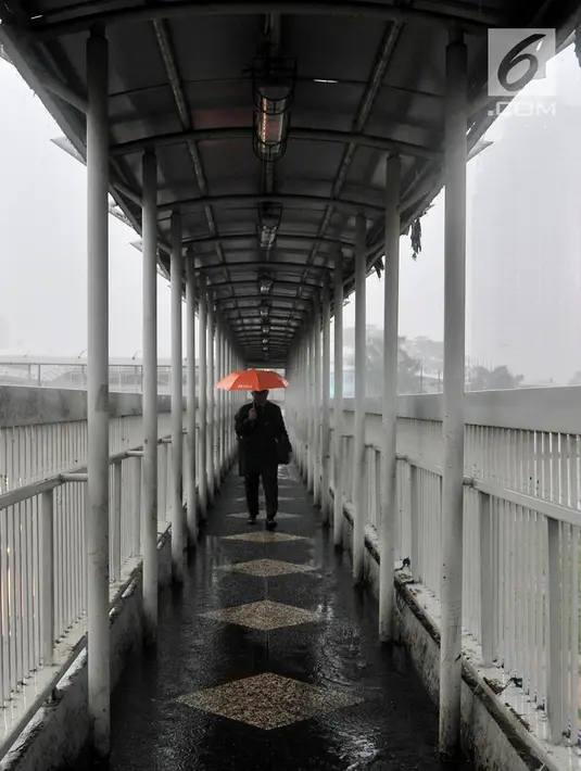 Pejalan kaki menggunakan payung saat hujan deras mengguyur kawasan Gatot Soebroto, Jakarta, Senin (11/2). Badan Meteorologi, Klimatologi, dan Geofisika (BMKG) memprediksi puncak musim hujan terjadi hingga Februari 2019. (Merdeka.com/Iqbal Nugroho)
