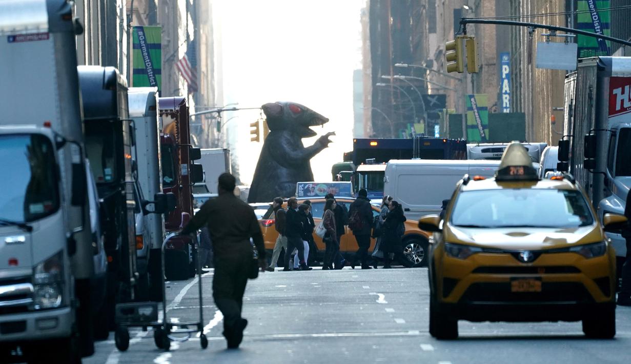 Balon tikus raksasa berjalan di tengah kota untuk diletakkan di luar kantor perusahaan sebagai simbol protes di New York, Kamis (26/12/2019). Serikat pekerja Amerika telah menggunakan balon tikus  untuk menyoroti praktik perburuhan yang tidak adil sejak 1990-an. (TIMOTHY A. CLARY/AFP)