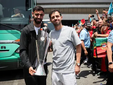 Pemain Timnas Portugal, Bruno Fernandes (kiri) dan Bernardo Silva berfoto bersama dengan fans sambil membawa trofi juara ajang Nations League 2025 setibanya di Bandara Lisbon, Portugal, Senin (09/06/2025) waktu setempat. (AFP/Carlos Costa)