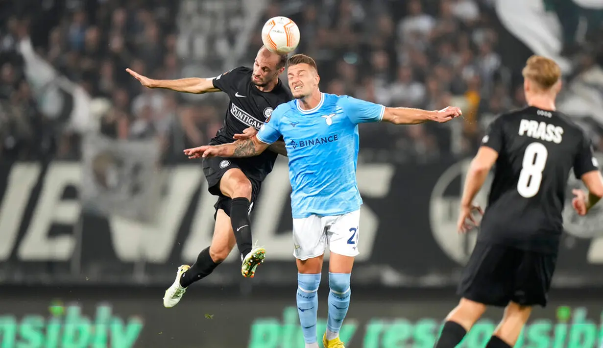 Pemain Sturm Graz Jon Gorenc Stankovic (kiri) berebut bola dengan pemain Lazio Sergej Milinkovic-Savic (tengah) pada pertandingan sepak bola Grup F Liga Europa di Merkur Arena, Graz, Austria, 6 Oktober 2022. Pertandingan berakhir imbang 0-0. (AP Photo/Florian Schroetter)