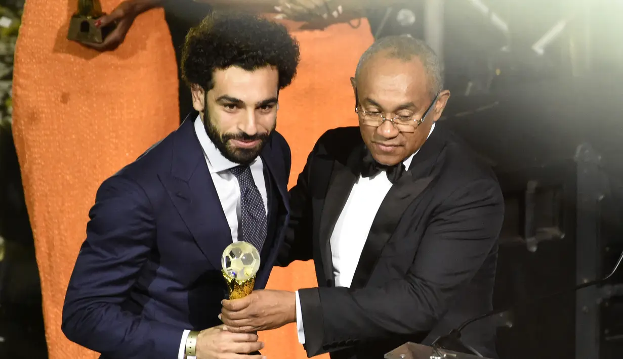 Mohamed Salah menerima trofi Pemain Terbaik Afrika 2017 dari Presiden CAF Ahmad Ahmad pada acara penghargaan tahunan Konfederasi Sepak Bola Afrika (CAF) di Ghana, Kamis (4/1). Salah membawa pulang penghargaan itu untuk pertama kali. (PIUS UTOMI EKPEI/AFP)