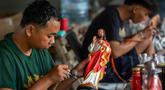 Para pekerja menyemprotkan cat ke patung-patung rohani di bengkel kerajinan Studio Malta Jaya di Bantul, Yogyakarta, pada Kamis 18 Desember 2025. Jelang perayaan Natal 2025, kesibukan terlihat di bengkel kerajinan Studio Malta Jaya di Bantul, Yogyakarta. (DEVI RAHMAN/AFP)