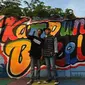 Para remaja berswafoto dengan latar gambar mural/grafiti yang ada di Kampung Bekelir, Jalan Perintis Kemerdekaan, Kota Tangerang, Banten, Selasa (17/4). Jumlah mural/grafiti di kampung ini sekarang mencapai 1.121 gambar. (Merdeka.com/Arie Basuki)