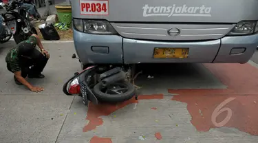 Bus Transjakarta bernomer polisi B 7058 IV menabrak pengendara sepeda motor di kawasan permata hijau, Jakarta, Jumat (27/3/2015). Sejumlah warga sedang melakukan evakuasi speda motor yang berada di dalam bus transjakarta. (Liputan6.com/Johan Tallo)