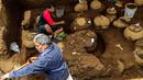 Pekerja Nicaraguan Institute of Culture (INC) menggali puluhan tembikar yang ditemukan di situs pemakaman zaman pra-Kolombia berusia lebih dari 1.200 tahun di lokasi pembangunan Stadion Bisbol Nasional yang baru di Managua, Selasa (20/6). (INTI OCON/AFP)