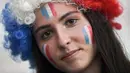 Suporter wanita melukis bendera Prancis di wajahnya sebelum menyaksikan pertandingan melawan Norwegia pada grup A Piala Dunia Wanita 2019 di Stadion Nice, Prancis (12/6/2019). Dalam pertandingan ini Prancis menang tipis atas Norwegia 2-1. (AFP Photo/Christophe Simon)