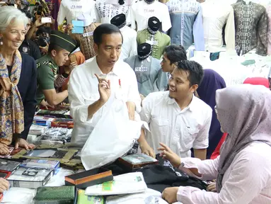 Presiden Jokowi menemani Direktur Pelaksana IMF Christine Lagarde memilih baju koko di salah satu toko Blok A Pasar Tanah Abang, Jakarta, Senin (26/2). Baju koko tersebut dibeli Lagarde sebagai oleh-oleh untuk sang suami. (Liputan6.com/Angga Yuniar)