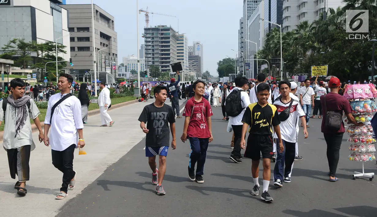 Sejumlah remaja beraktivitas di antara peserta Reuni 212 saat Car Free Day (CFD) di kawasan Jakarta, Minggu (2/12). Warga tetap memadati area Car Free Day  dari Bundaran HI-Sudirman meskipun ada aksi Reuni 212. (Liputan6.com/Angga Yuniar)