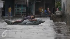 Seorang anak bermain saat banjir menggenangi kawasan Pasar Buncit, Jakarta Selatan, Selasa (9/2/2016). Banjir menggenangi kawasan tersebut hingga setinggi 100 cm akibat luapan Kali Kemang. (Liputan6.com/Gempur M Surya)