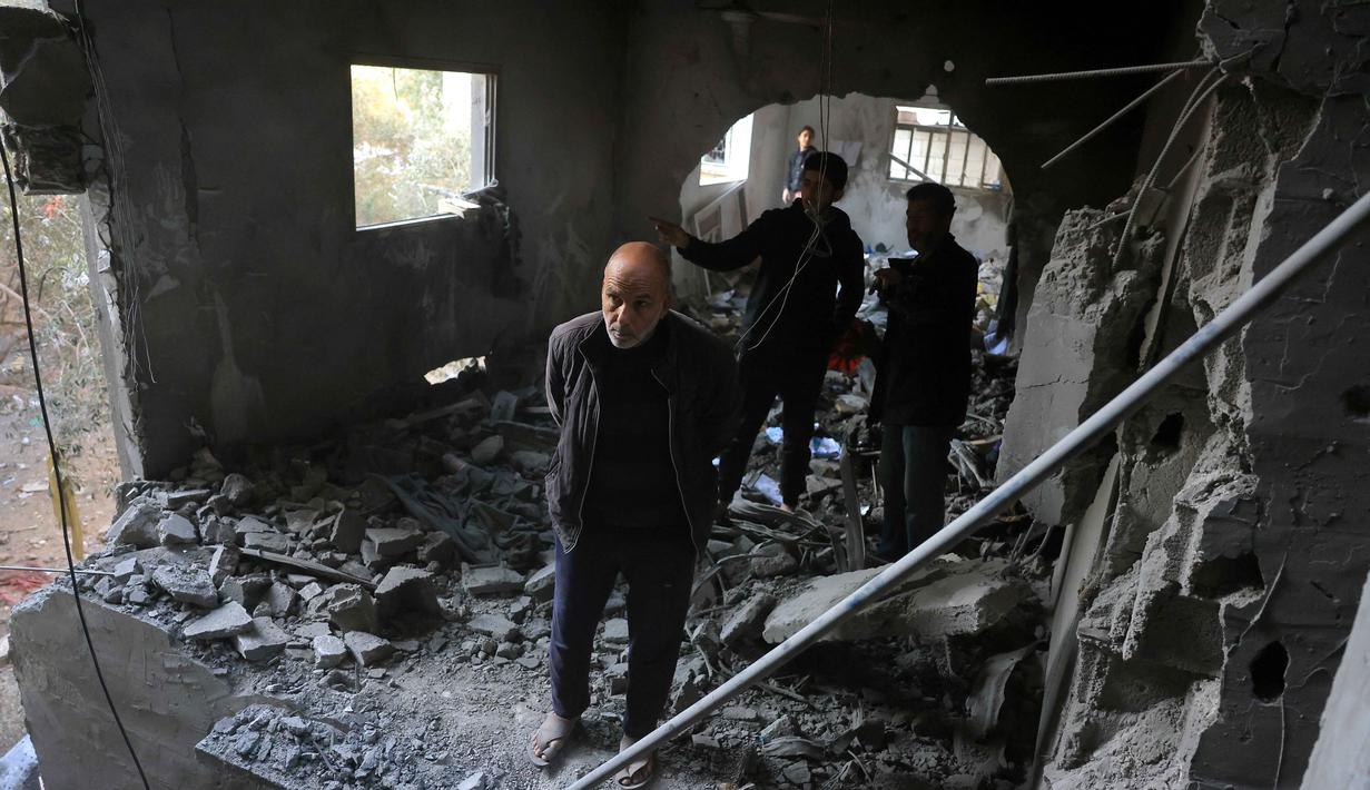Hingga Kamis 15 Januari 2025, jumlah korban tewas mencapai 71.441 jiwa sejak awal konflik antara Israel dan Hamas pada 7 Oktober 2023. Tampak dalam foto, seorang pria Palestina berdiri memandang dari tempat yang dulunya merupakan tembok bangunan, setelah serangan militer Israel terhadap rumah keluarga al-Houli, di mana empat orang dilaporkan tewas, di sebelah barat Deir al-Balah, di Jalur Gaza tengah pada Jumat 16 Januari 2026. (BASHAR TALEB/AFP)