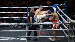 Petarung Malaysia, Ammarul Shafiq, melepaskan tendangan keras ke bagian rahang kiri petarung Indonesia, Serieal Effendy pada pertandingan Byon Combat Showbiz Vol. 6 di Tennis Indoor Senayan, Jakarta, Sabtu (22/10/2025). (Bola.com/M Iqbal Ichsan)