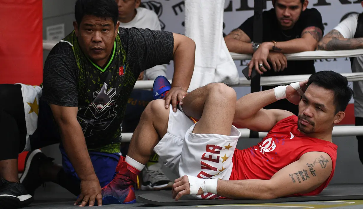 Petinju Manny Pacquiao melakukan pemanasan dengan pengawasan teman lama Nonoy Neri selama sesi pelatihan di gym di Manila, (17/5). Pacquiao akan bertanding melawan petinju Argentina Lucas Matthysse. (AFP Photo/Ted Aljibe)