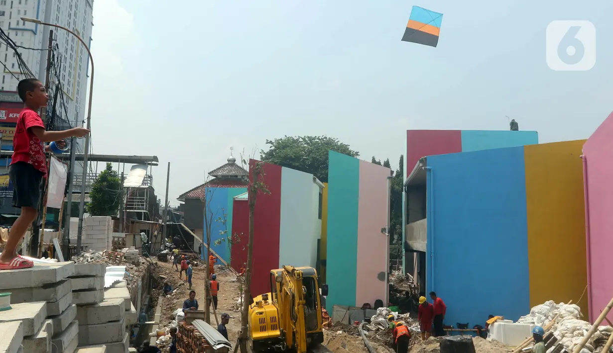Seorang anak bermain layang-layang saat para pekerja mengerjakan pembangunan rumah bagi korban kebakaran di Kampung Gembira Gembrong, Jakarta, Rabu (14/9/2022). Menurut data Pemprov DKI Jakarta, pembangunan 138 unit rumah bagi korban kebakaran di permukiman Kampung Gembira Gembrong telah mencapai 90 persen dan akan segera dihuni kembali pada akhir September 2022. (Liputan6.com/Herman Zakharia)