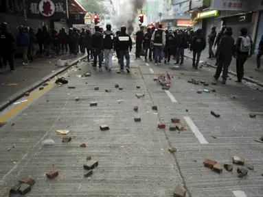 Sejumlah batu terlihat di belakang polisi anti huru hara setelah bentrokan dengan pengunjuk rasa di Mongkok, Hong Kong, Selasa (9/2). Bentrokan dimulai ketika pemerintah daerah mencoba untuk menertibkan PKL yang beroperasi. (REUTERS/Liau Chung-ren)