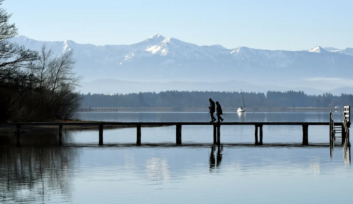 Pejalan kaki berjalan melewati panorama alpine di danau Starnberger See dekat desa kecil Bavaria Seeshaupt, Jerman (25/2). Gunung tertinggi di Alpen adalah Mont Blanc dengan ketinggian 4.808 m di perbatasan Prancis-Italia. (AFP Photo/Christof Stache)