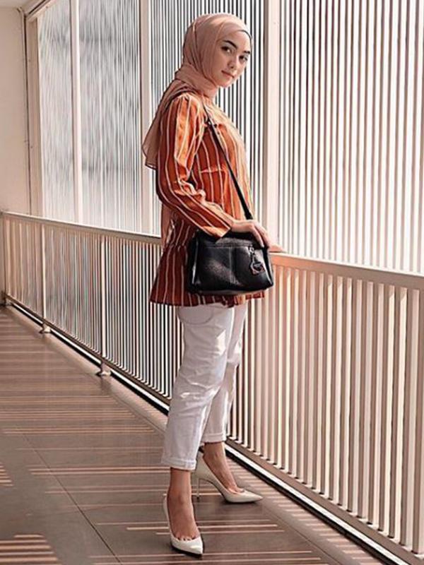Citra Kirana juga menyukai outfit dengan warna cerah seperti kemeja oranye yang dipadukan dengan hijab krem, tas hitam, celana dan heels berwarna putih. (Liputan6.com/IG/@citraciki)