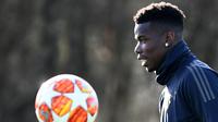 Pemain Manchester United, Paul Pogba, mengamati bola saat latihan jelang laga 16 besar Liga Champions di Kompleks Carrington, Manchester, Senin (11/2). MU akan menjamu PSG pada leg pertama di Stadion Old Trafford. (AFP/Franck Fife)