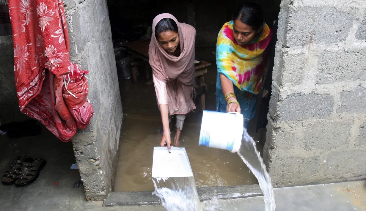 Dua wanita membuang air dari rumah mereka setelah hujan deras di Karachi, Pakistan, Selasa (30/7/2019). Hujan deras terjadi pada hari Senin dan berlanjut pada hari Selasa dan air limbah membanjiri sebagian besar jalan di Karachi, ibukota provinsi Sindh selatan. (AP/Photo/Fareed Khan)