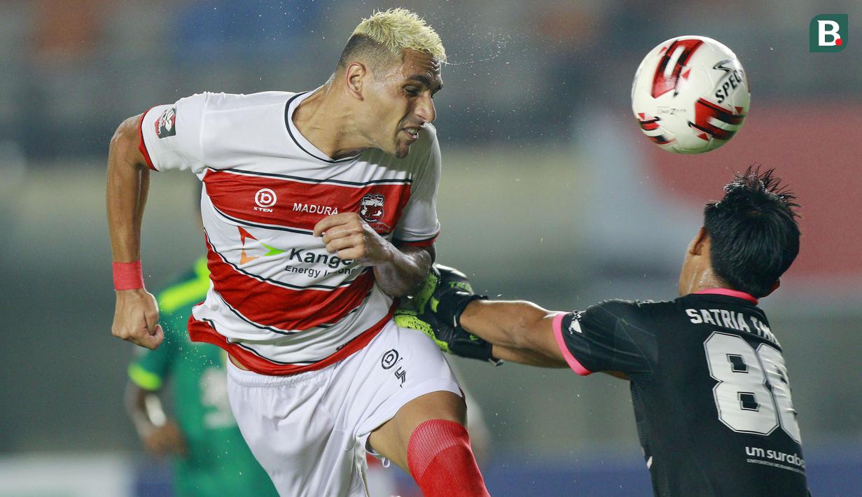 Bek Madura United, Jaimerson Da Silva Xavier (kiri) duel udara dengan kiper Persebaya Surabaya, Satria Tama, dalam pertandingan Babak Penyisihan Piala Menpora 2021 Grup C di Stadion Si Jalak Harupat, Bandung, Minggu (28/3/2021). (Foto: Bola.com/M Iqbal Ichsan)