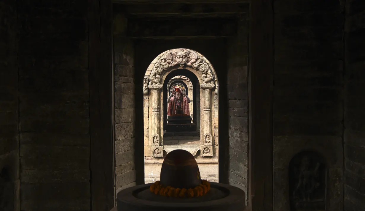 Seorang Sadhu (orang suci Hindu) berdoa pada malam festival Hindu Maha Shivaratri di Kuil Pashupatinath di Kathmandu (20/2/2020). Festival ini  didedikasikan untuk 'Malam Besar Siwa', dewa Hindu yang berdoa dan berpuasa bagi orang percaya. (AFP/Prakash Mathema)