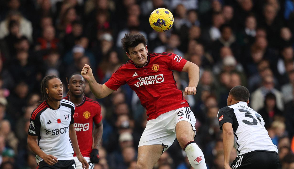 Pemain MU, Harry Maguire (tengah, berhasil mengamankan bola di udara dari jangkaun pemain Fulham dalam pekan ke-11 Premier League 2023/2024 yang berlangsung di Stadion Craven Cottage, London, Sabtu (4/11/2023) malam WIB. (AFP/Adrian Dennis)