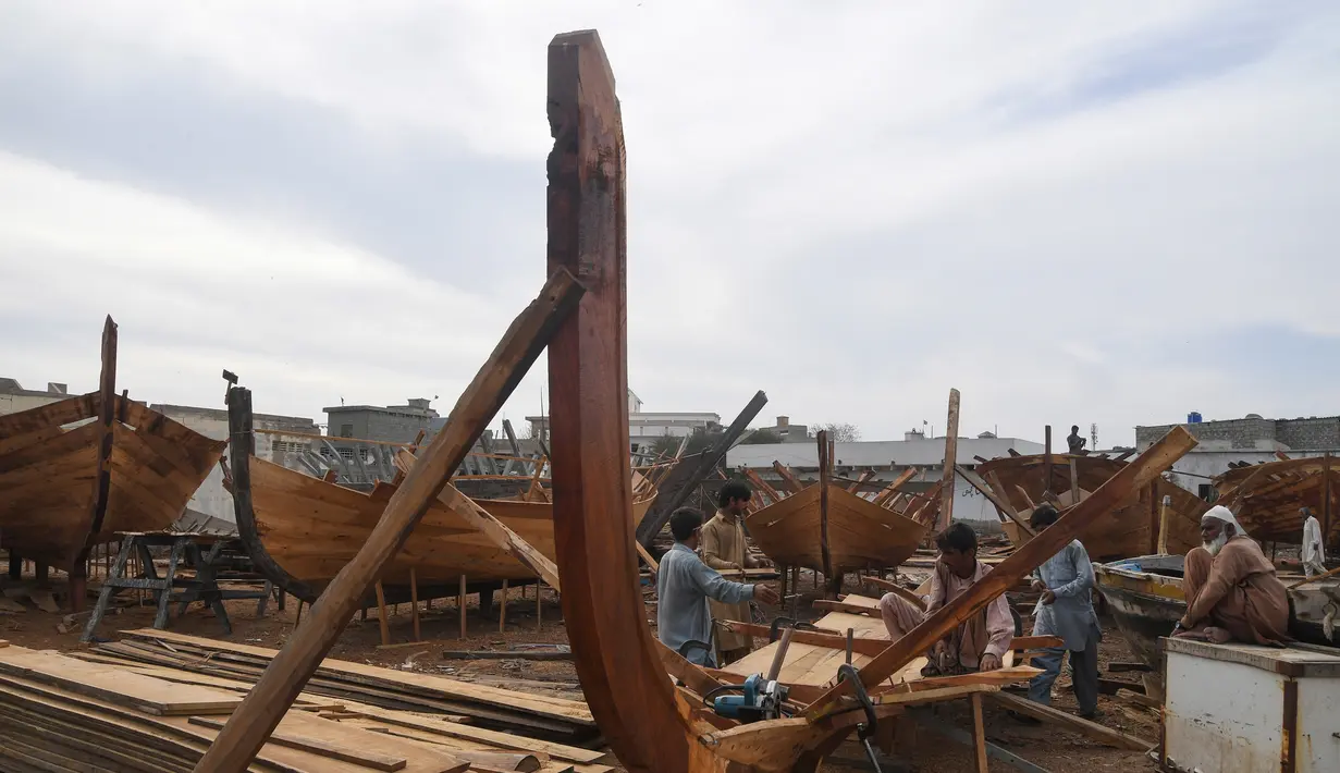 Tukang kayu Pakistan menyelesaikan pembuatan kapal penangkap ikan di sebuah pelabuhan di Karachi (3/4). Pembuatan kapal buatan Pakistan menghasilkan ratusan kapal setiap tahun untuk memenuhi permintaan industri perikanan setempat. (AFP Photo/Asif Hassan)