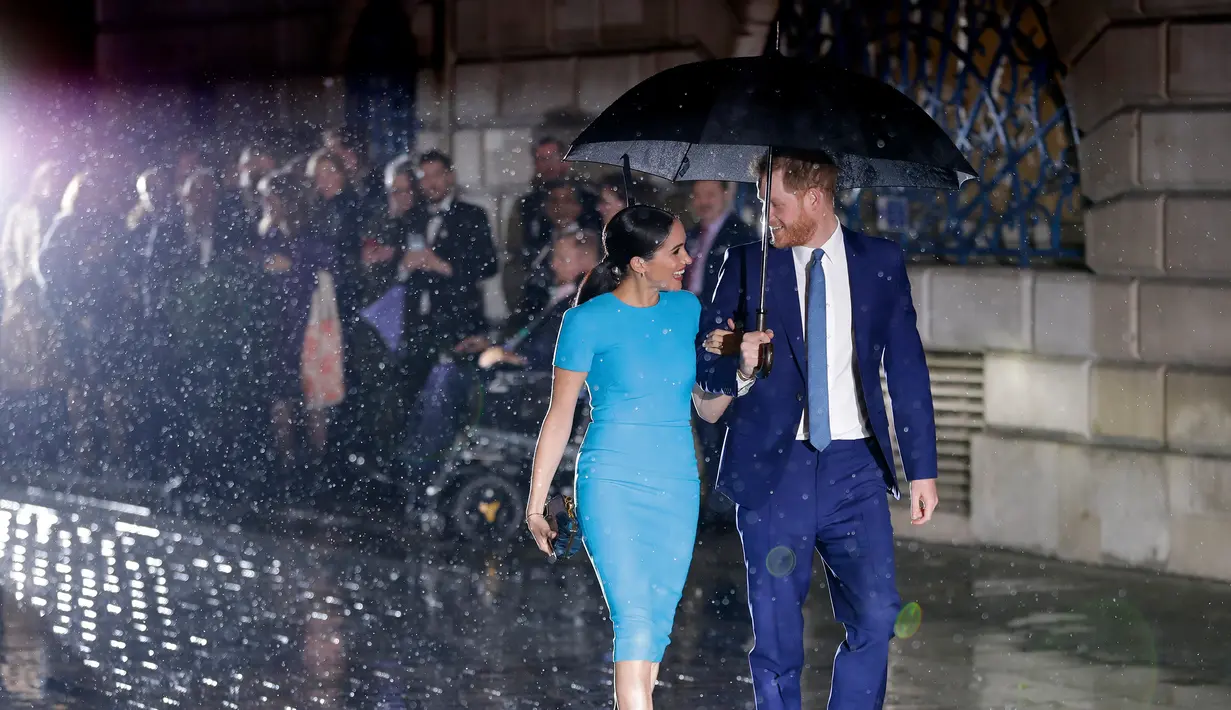 Pangeran Harry dan Meghan Markle sepayung berdua saat tiba di Endeavour Fund Awards, London, Inggris, Kamis (5/3/2020). Hujan lebat turun saat Pangeran Harry dan Meghan Markle tiba di lokasi. (AP Photo/Kirsty Wigglesworth)