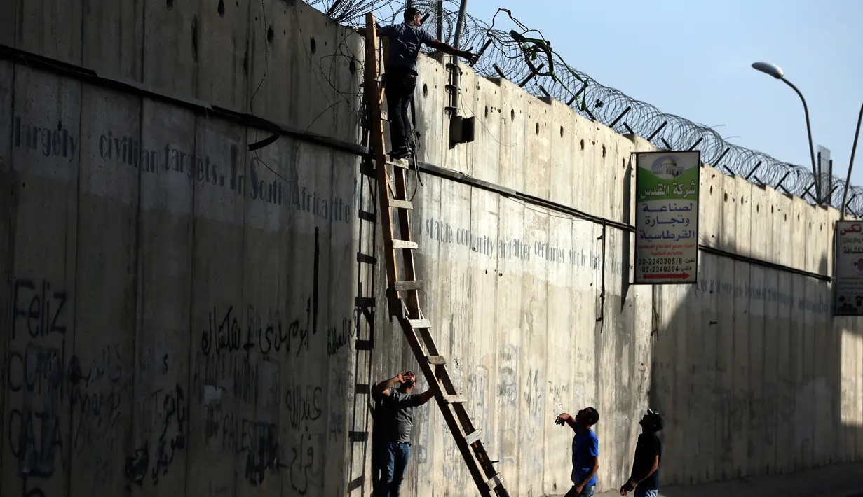 Pemuda Palestina berusaha memanjat tembok pembatas Israel saat berangkat untuk beribadah salat Jumat di Masjid Al-Aqsa, Yerusalem, Jumat (9/6). Para pemuda ini nekat memanjat untuk menghindari pengawasan tentara Israel. (AFP Photo/Abbas Momani)