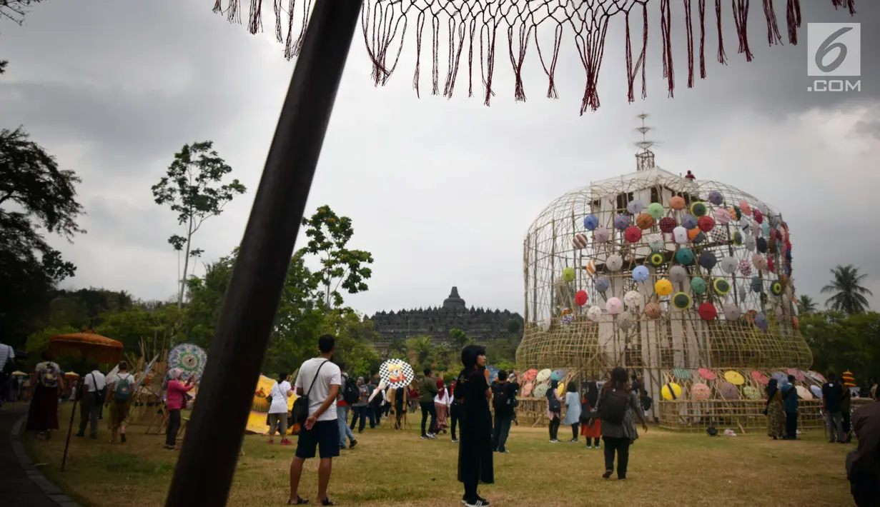 Pengunjung melihat dekorasi payung pada Festival Payung Indonesia 2018 di Taman Lumbini, Komplek Candi Borobudur, Magelang, Jumat (7/9). Festival yang digelar sejak 2014 ini bertujuan melestarikan payung tradisional yang mulai punah. (Liputan6.com/Gholib)