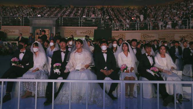 Sejumlah pasangan mengikuti kegiatan nikah massal di Cheong Shim Peace World Center di Gapyeong, Korea Selatan, Jumat, (7/2/2020). Meski memakai masker untuk mencegah virus corona, para pasangan pengantin tampak bahagia di acara tersebut. (AP Photo/Ahn Young-joon)