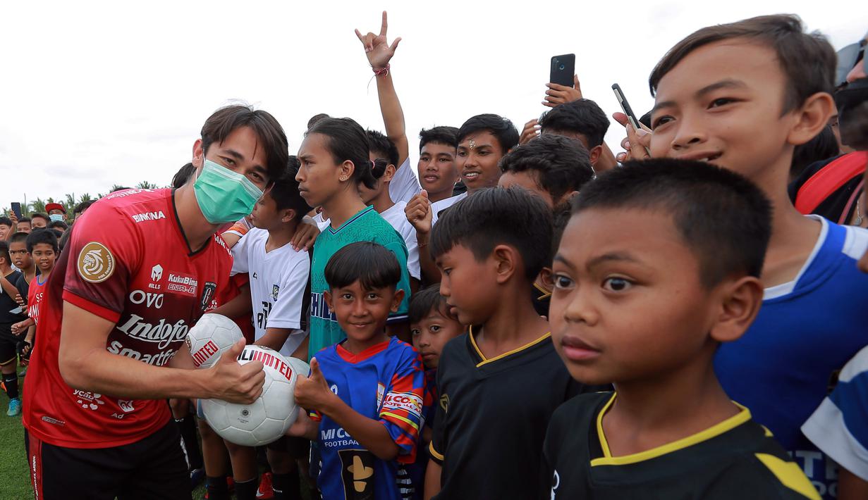 Pemain Bali United, Gavin Kwan Adsit, menyerahkan bola kepada pesepak bola cilik di Training Ground Bali United, Gianyar, Senin (28.03/2022). (Bola.com/ M Iqbal Ichsan)