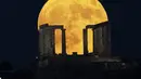 Bulan purnama terbesar atau supermoon muncul di belakang Kuil Poseidon di Tanjung Sounio, selatan Athena, Senin (19/8/2024). (AP Photo/Michael Varaklas)