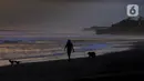 Warga membawa anjingnya berjalan di tepi Pantai Pasut, Tabanan, Bali, Sabtu (4/9/2021). Menteri Pariwisata dan Ekonomi Kreatif Sandiaga Uno menyebut okupansi di berbagai destinasi wisata di Bali masih mengalami kontraksi signifikan. (merdeka.com/Arie Basuki)