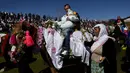 Pria muslim Bulgaria menggendong putra mereka saat menunggang kuda selama upacara sunat massal untuk anak laki-laki di Desa Ribnovo, 11 April 2021. Penduduk Desa Ribnovo adalah muslim berbahasa Bulgaria, kadang-kadang disebut sebagai "Pomaks" atau "orang yang menderita". (Nikolay DOYCHINOV/AFP)