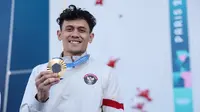 Atlet panjat tebing Indonesia, Veddriq Leonardo, memamerkan medali emas Olimpiade Paris 2024, yang diraihnya dari nomor speed putra, Kamis (8/8/2024). (NOC Indonesia)