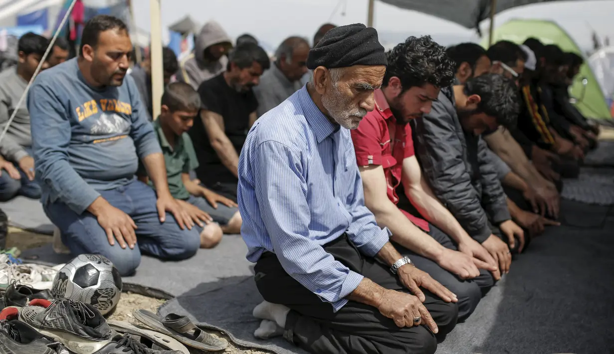 Sejumlah imigran saat menggelar salat Jumat di sebuah kamp darurat perbatasan Yunani-Makedonia,desa Idomeni, Yunani (8/4). Meski tengah mencari perlindungan, mereka tak melalaikan kewajibannya sebagai seorang muslim. (REUTERS/Marko Djurica)