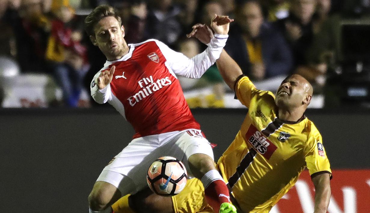 Duel pemain Arsenal, Nacho Monreal (kiri) dan pemain Sutton United, Nicky Bailey pada putaran kelima Piala FA di Gander Green Lane stadium, London; (20/2/2017). Arsenal menang 2-0. (AP/Matt Dunham)