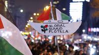Seorang pengunjuk rasa memegang plakat penghormatan kepada Global Sumud Flotiila saat berunjuk rasa dalam solidaritas kepada warga Palestina dan mengutuk pencegatan armada oleh tentara Israel, di Istanbul, Turki pada 2 Oktober 2025. (KEMAL ASLAN/AFP)
