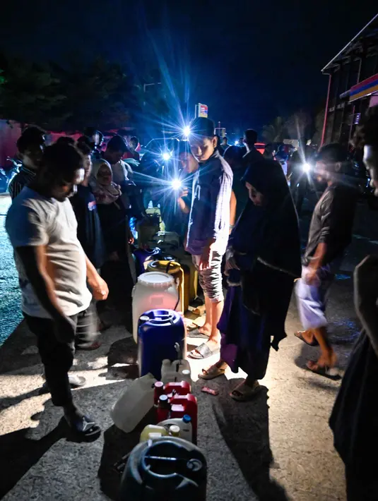 Situasi kelangkaan ini dipicu oleh dua faktor utama, yaitu lonjakan permintaan dan hambatan distribusi akibat bencana banjir dan tanah longsor yang melanda sejumlah wilayah di Sumatra. Tampak dalam foto, warga terdampak banjir mengantre untuk mendapatkan bahan bakar di sebuah Stasiun Pengisian Bahan Bakar Umum (SPBU) di Samahani, Provinsi Aceh, pada 2 Desember 2025. (CHAIDEER MAHYUDDIN/AFP)