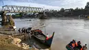 Untuk sementara, warga terpaksa menggunakan perahu nelayan sebagai sarana penyeberangan darurat di sungai. Tampak dalam foto, para penumpang menaiki perahu untuk menyeberangi Sungai Peusangan di Kuta Blang, Kabupaten Bireuen, Provinsi Aceh, pada Selasa 9 Desember 2025. (CHAIDEER MAHYUDDIN/AFP)