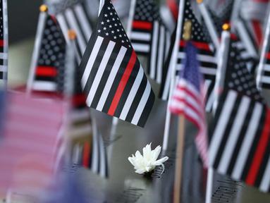 Bunga dan bendera Amerika Serikat terlihat di atas nama-nama korban serangan teroris 9/11 di kolam refleksi Menara Selatan selama Upacara Peringatan Tahunan 9/11 di Museum dan Monumen Nasional 9/11 di Kota New York pada 11 September 2025. (Michael M. Santiago/Getty Images North America/Getty Images via AFP)