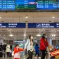 Penerbangan dari Wuhan Ditutup: Pelancong berjalan melintasi papan informasi tentang penerbangan dari Wuhan telah dibatalkan di Bandara Internasional Ibu Kota Beijing pada Kamis (23/1/2020). (AP/Mark Schiefelbein)