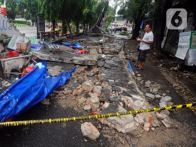 Warga berdoa di lokasi robohnya tembok SPBU di Jalan Tebet Barat Dalam Dua, Jakarta Selatan, Minggu (21/1/2024) siang. Robohnya tembok sepanjang sekitar 50 meter dan tinggi 3 meter saat angin kencang itu menyebabkan tiga warga tewas. (merdeka.com/Arie Basuki)