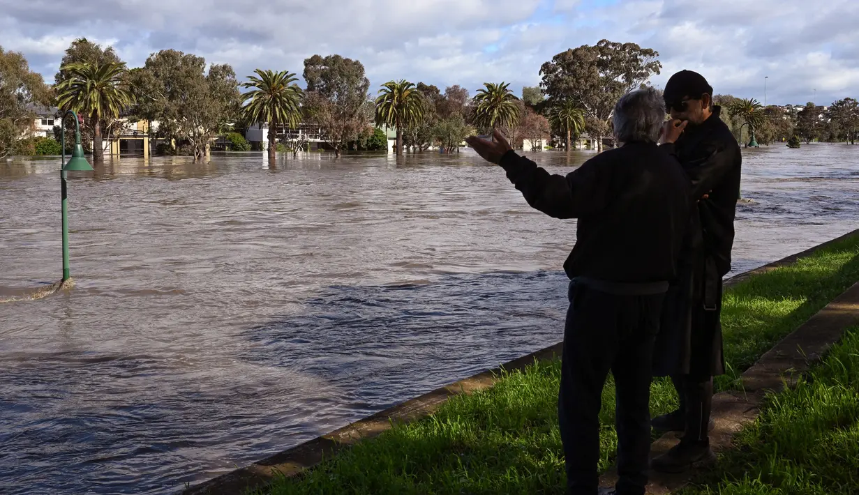 Orang-orang melihat daerah banjir di pinggiran Kota Melbourne, Maribyrnong, Australia, Jumat (14/10/2022). Banjir pun dikhawatirkan berlangsung hingga akhir pekan ini. (William WEST/AFP)