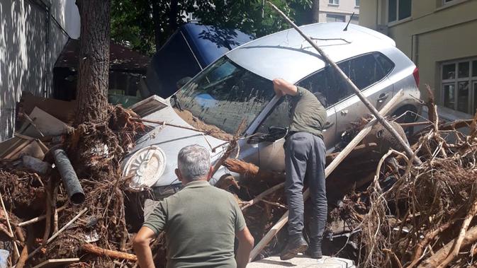 Orang-orang berupaya mengevakuasi mobil dari puing-puing setelah diterjang banjir di Provinsi Giresun, kawasan Laut Hitam, Turki (23/8/2020). Banjir yang melanda Giresun pada Minggu (23/8) menewaskan enam orang, termasuk dua personel Gendarmerie. (Xinhua)
