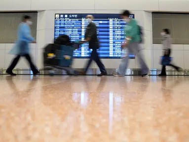 Wisatawan asing dan staf bandara berjalan di Bandara Internasional Haneda, Tokyo, Selasa (11/10/2022). Pembatasan ketat perbatasan Jepang dilonggarkan, memungkinkan wisatawan dengan mudah masuk untuk pertama kalinya sejak dimulainya pandemi COVID-19. (AP Photo/Eugene Hoshiko)