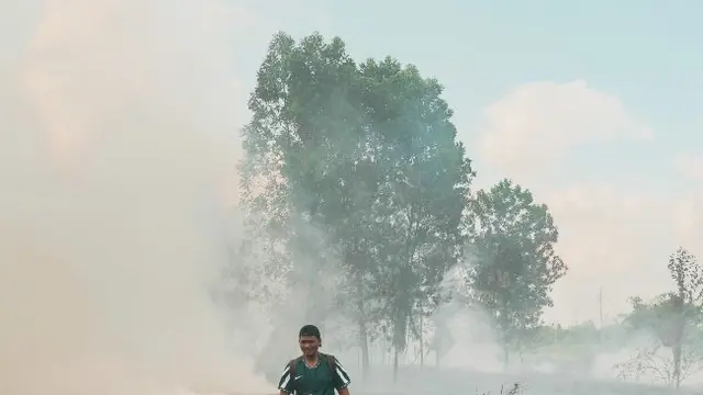 Seorang warga berada di lokasi kebakaran lahan di Kota Pekanbaru.