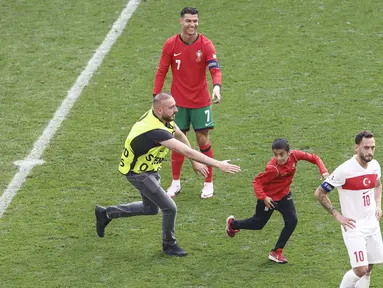Kemenangan Portugal atas Turki pada laga Euro 2024 diwarnai dengan momen fans menerobos ke dalam lapangan untuk berfoto dengan Cristiano Ronaldo. (AFP/Kenzo Tribouillard)
